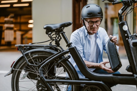 Senior man changing battery on electric bicycle stock photo